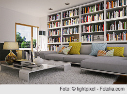 Wohnzimmer mit Sitzgarnitur und großem Bücherregal im Hintergrund